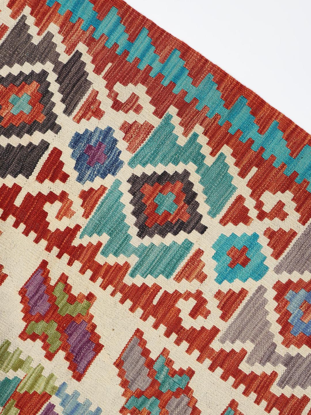 A large, colourful hand-woven Afghan Kelim rug with geometric diamond patterns.