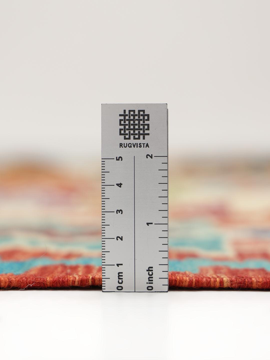 A large, colourful hand-woven Afghan Kelim rug with geometric diamond patterns.