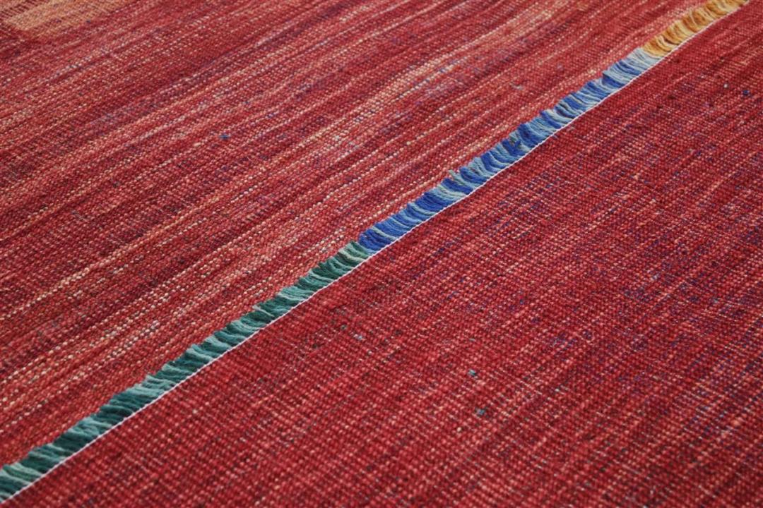 Een rood Afghaans kelim vloerkleed met moderne lineaire patronen