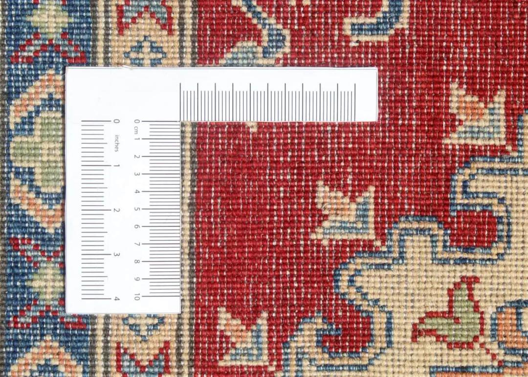 Een groot rechthoekig handgeknoopt Afghaans Kazak-tapijt met een dieprood veld en geometrische medaillons.