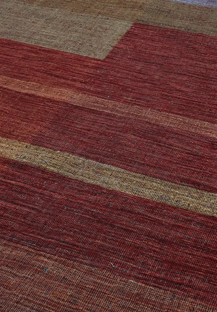 Håndvævet afghansk tæppe med et moderne geometrisk mønster i nuancer af rød og jordfarver