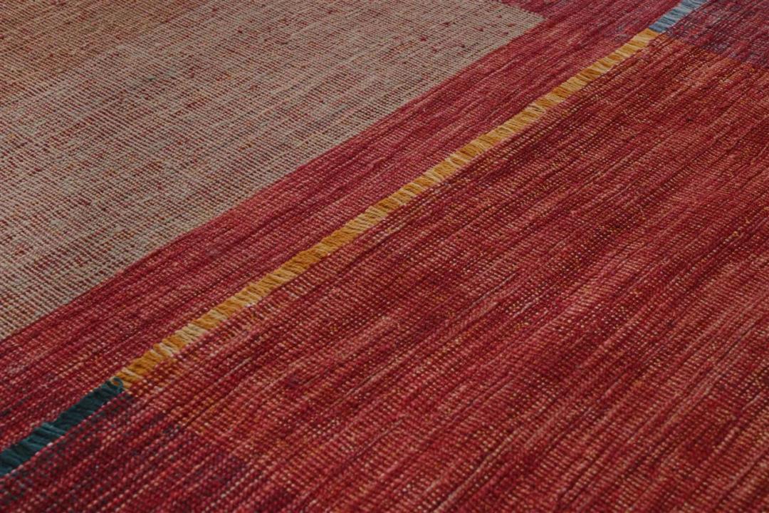 Håndvævet afghansk tæppe med et moderne geometrisk mønster i nuancer af rød og jordfarver