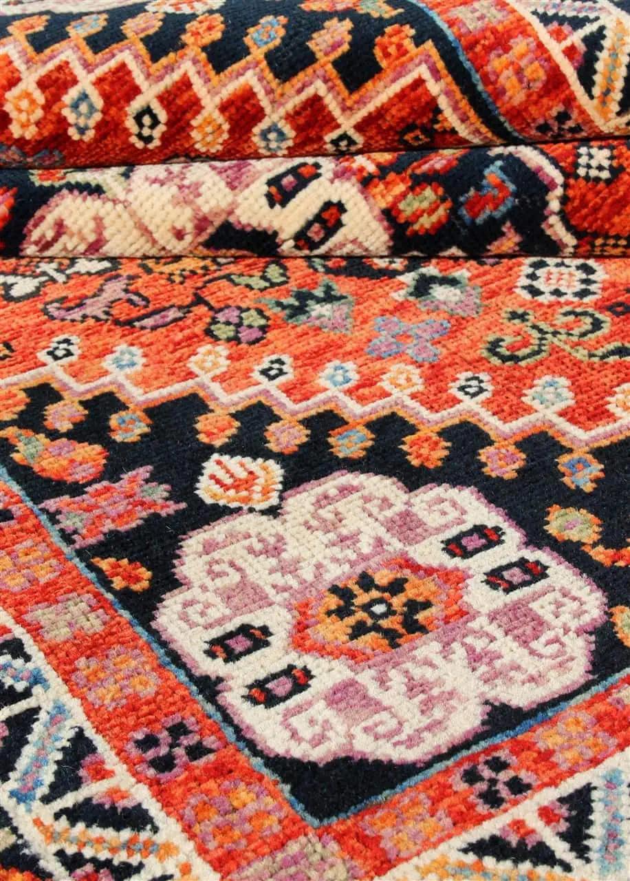 Covor Kazak înnodat manual din Afganistan, cu un design geometric vibrant în nuanțe de roșu și negru.