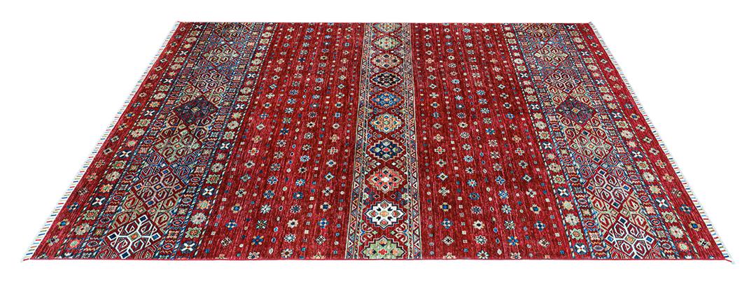 Una alfombra afgana anudada a mano con un vibrante campo rojo y patrones geométricos