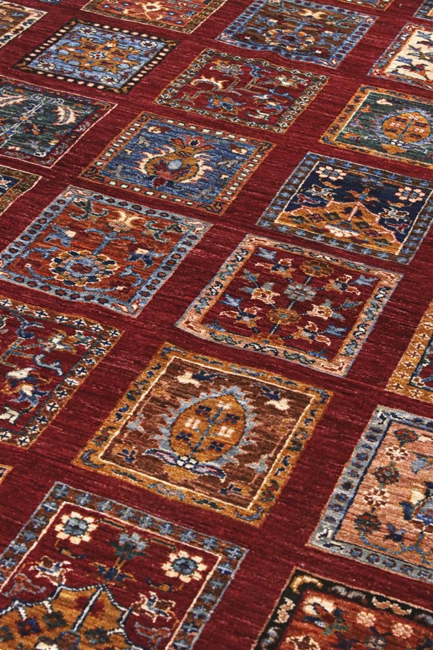 Hand-knotted Middle Eastern rug with a red field and decorative multi-coloured geometric panels