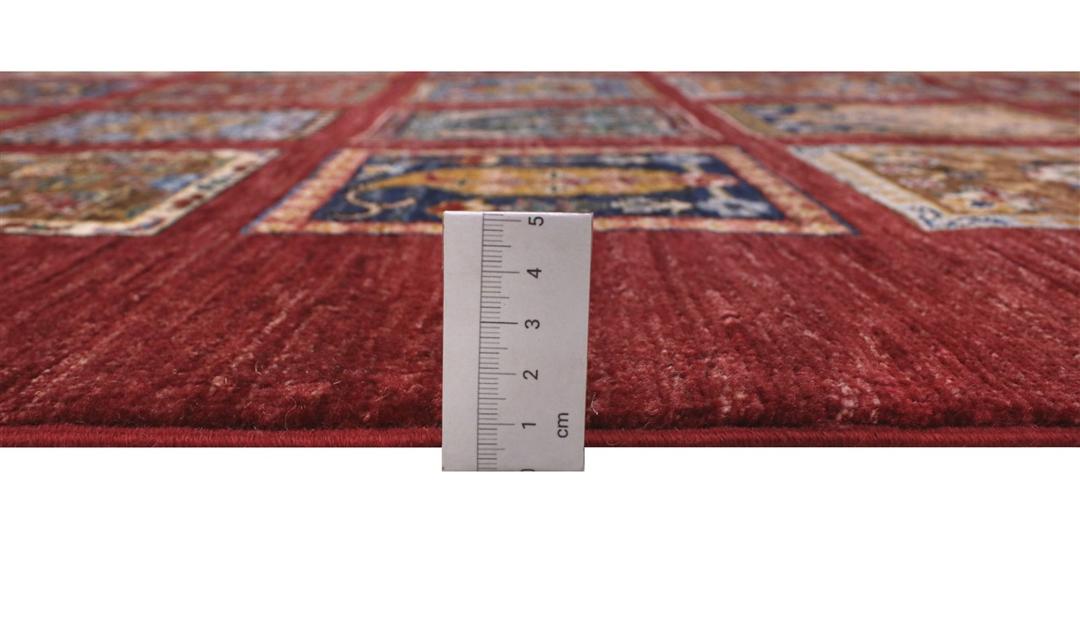 Hand-knotted Middle Eastern rug with a red field and decorative multi-coloured geometric panels