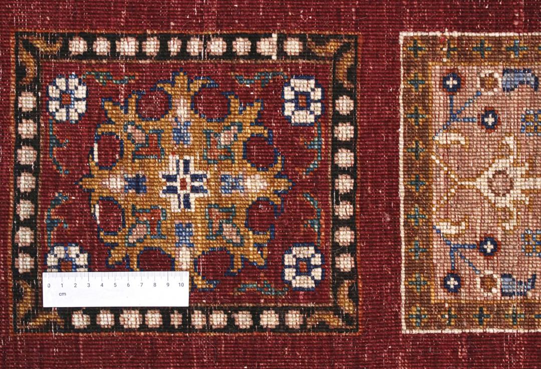 Hand-knotted Middle Eastern rug with a red field and decorative multi-coloured geometric panels