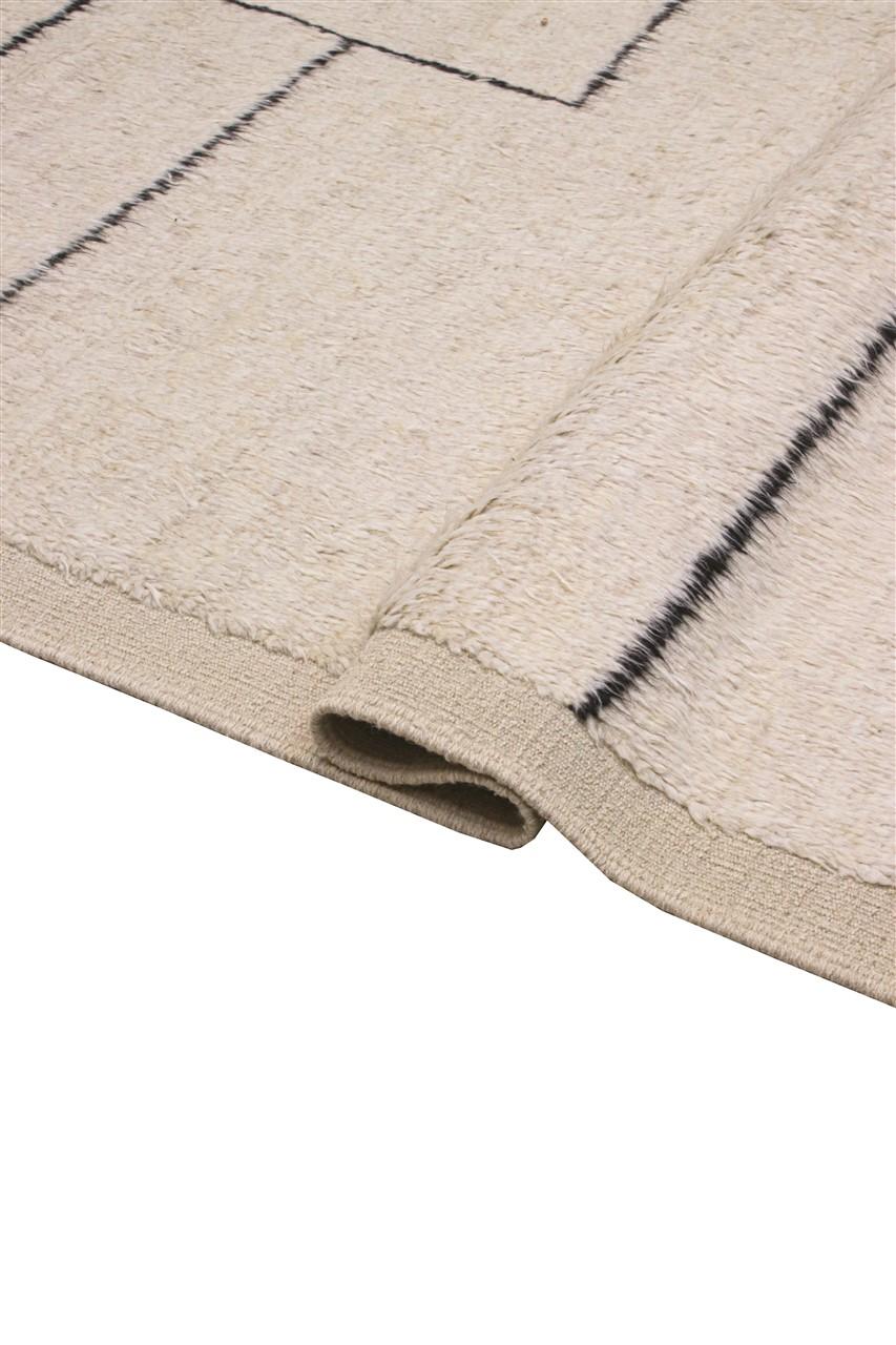 Et håndknyttet tæppe i Berber-stil fra Afghanistan med beige luv af uld og sorte minimalistiske linjer.