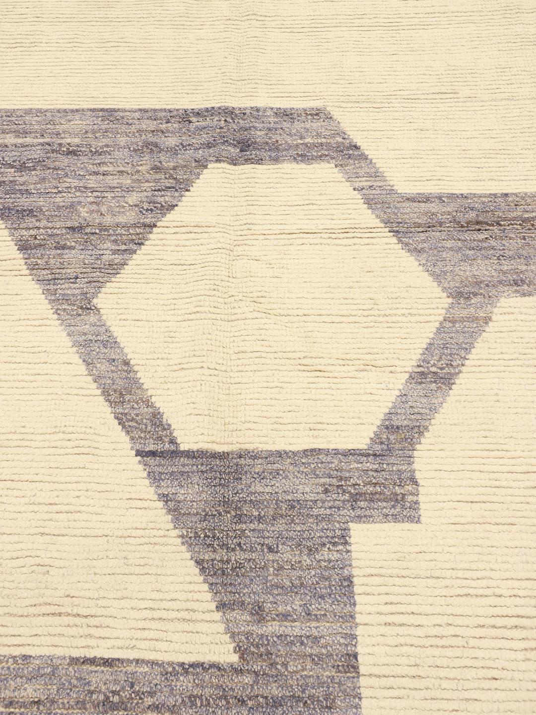 A large hand-knotted Afghan rug featuring a geometric pattern in beige and grey