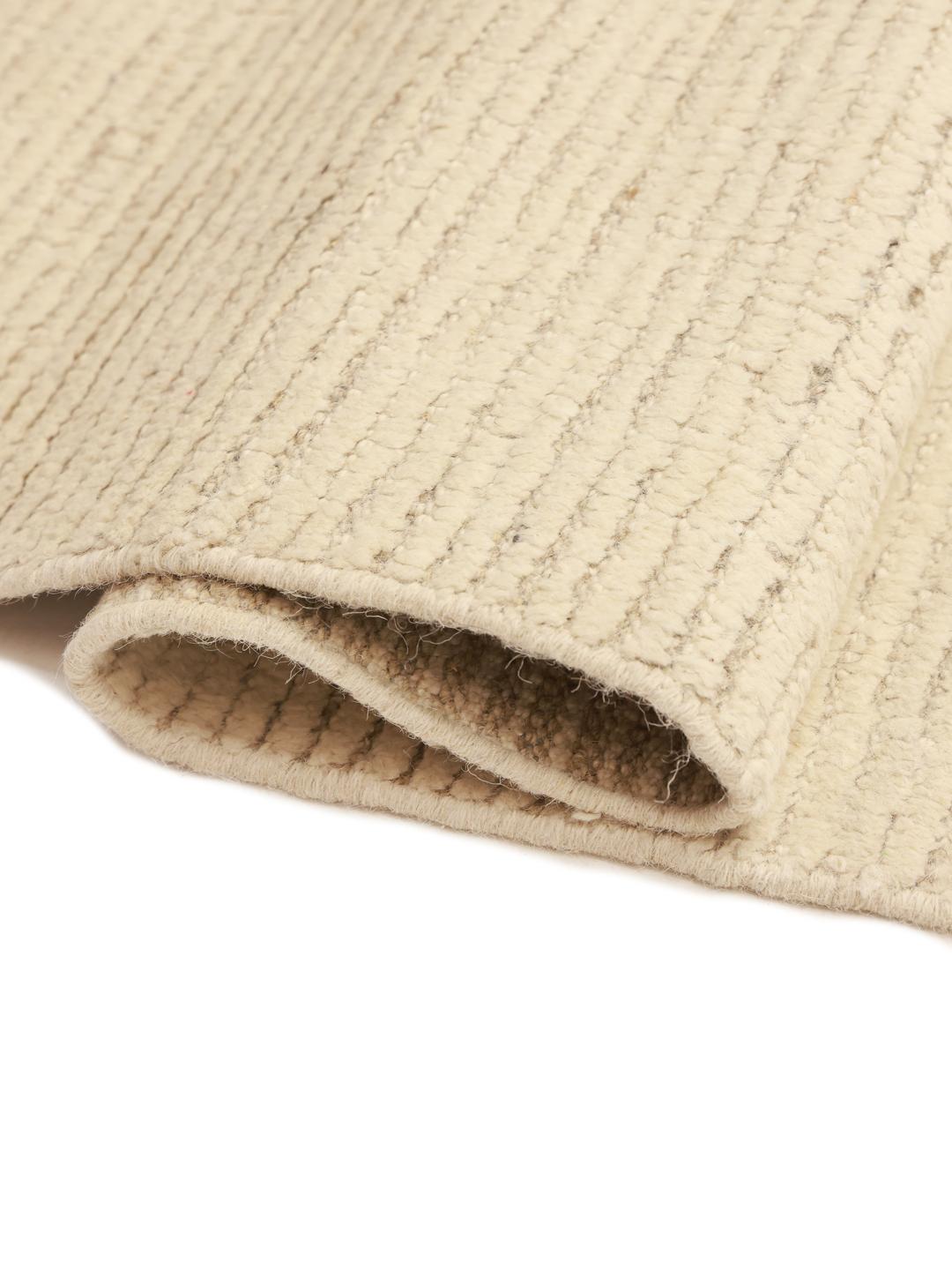 A large hand-knotted Afghan rug featuring a geometric pattern in beige and grey