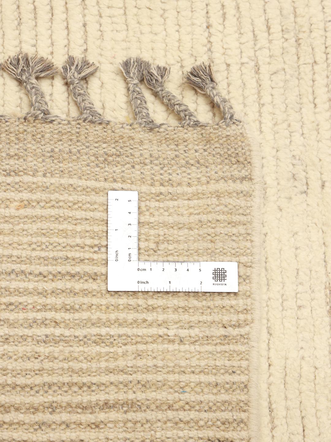 A large hand-knotted Afghan rug featuring a geometric pattern in beige and grey