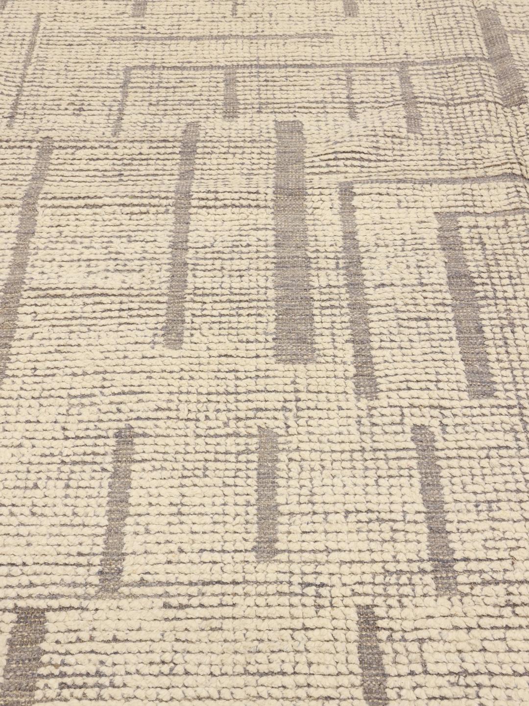 Un grand tapis style berbère noué à la main provenant d'Afghanistan, arborant un motif de lignes géométriques dans des tons beige et marron neutres.