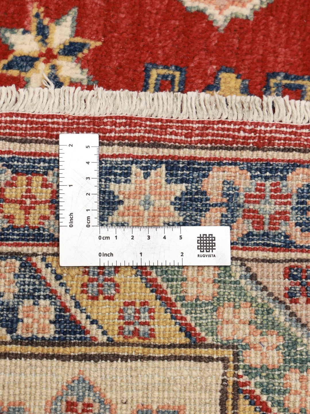 Un covor Kazak înnodat manual din Afganistan, prezentând un câmp roșu și medalioane geometrice colorate.