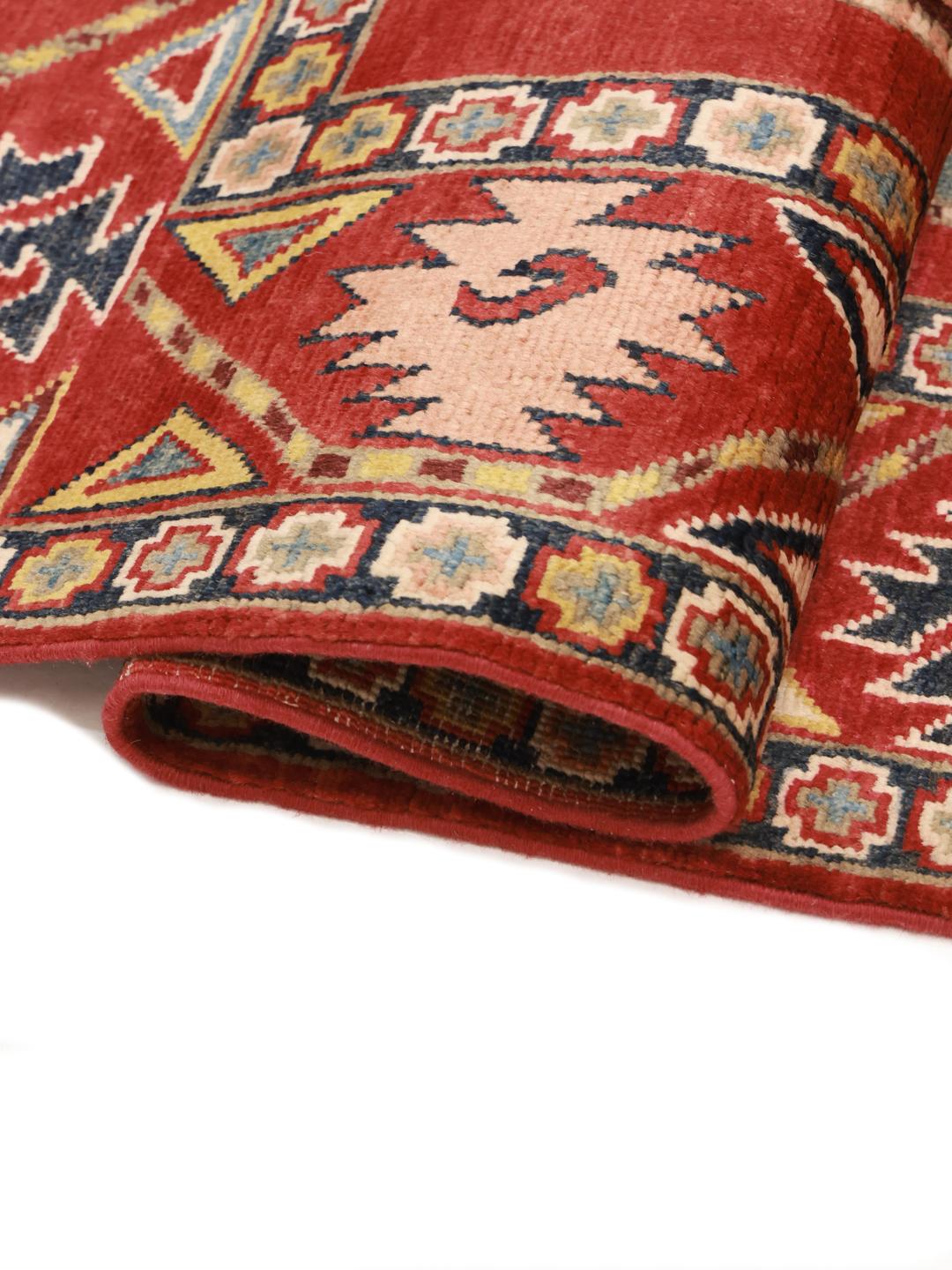 A hand-knotted Kazak rug from Afghanistan with a vibrant red field and geometric patterns.