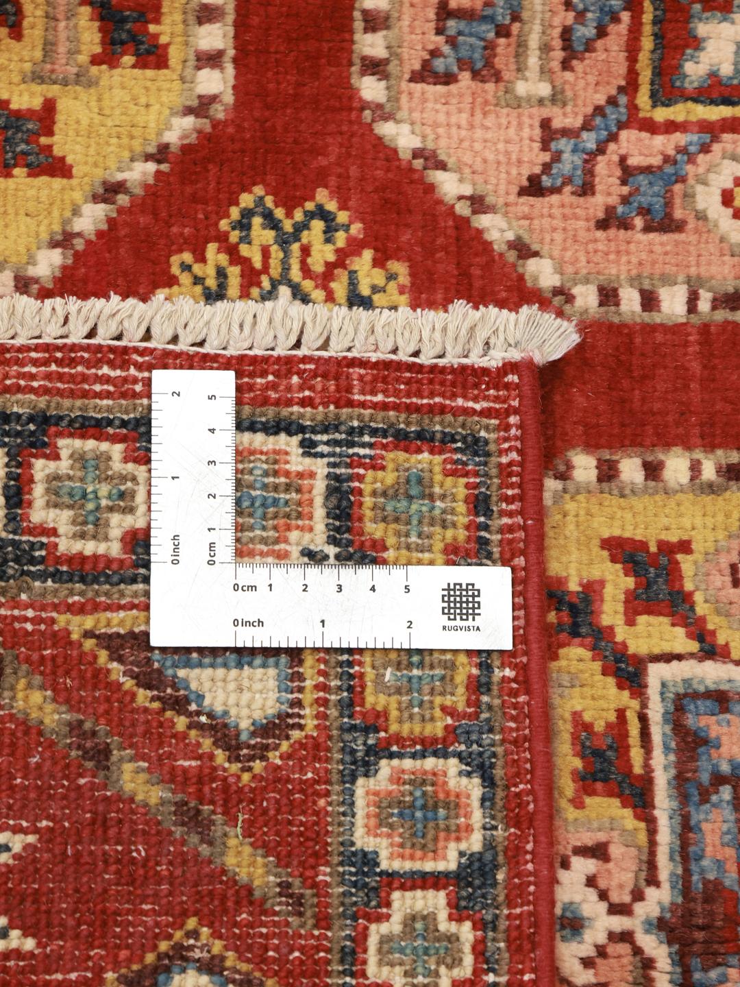 A hand-knotted Kazak rug from Afghanistan with a vibrant red field and geometric patterns.