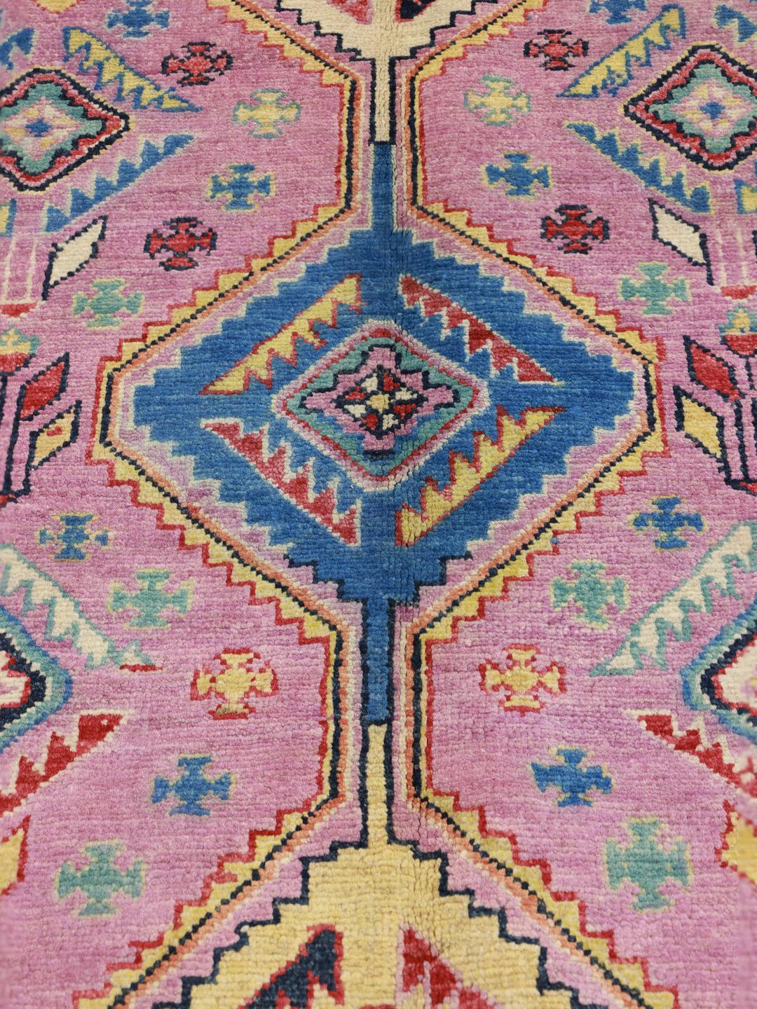 Ein rechteckiger Kazak-Teppich aus Afghanistan mit einem rosa Fond und geometrischen Rautenmedaillons.