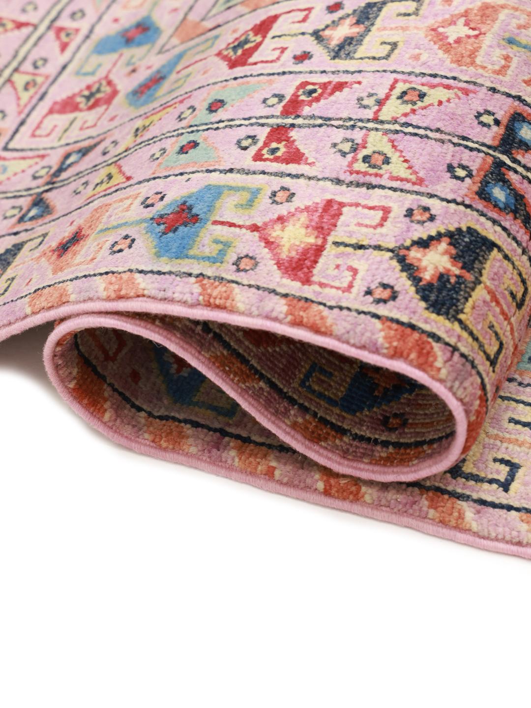 Ein rechteckiger Kazak-Teppich aus Afghanistan mit einem rosa Fond und geometrischen Rautenmedaillons.