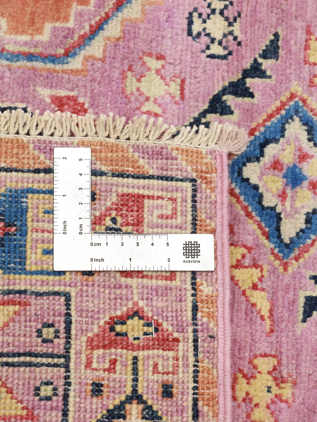 Ein rechteckiger Kazak-Teppich aus Afghanistan mit einem rosa Fond und geometrischen Rautenmedaillons.