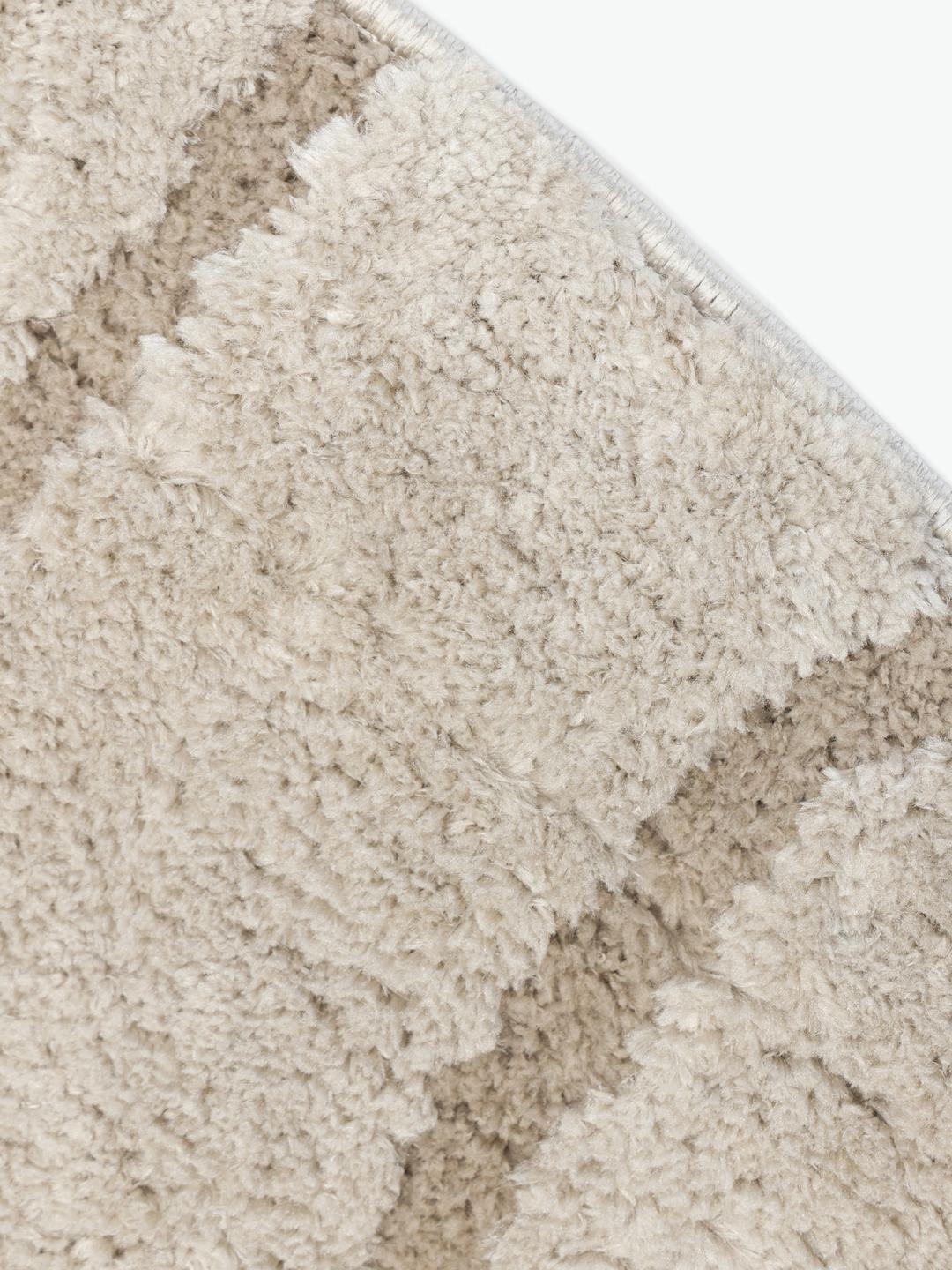 Rundt beige tæppe med et abstrakt high-low-luvmønster