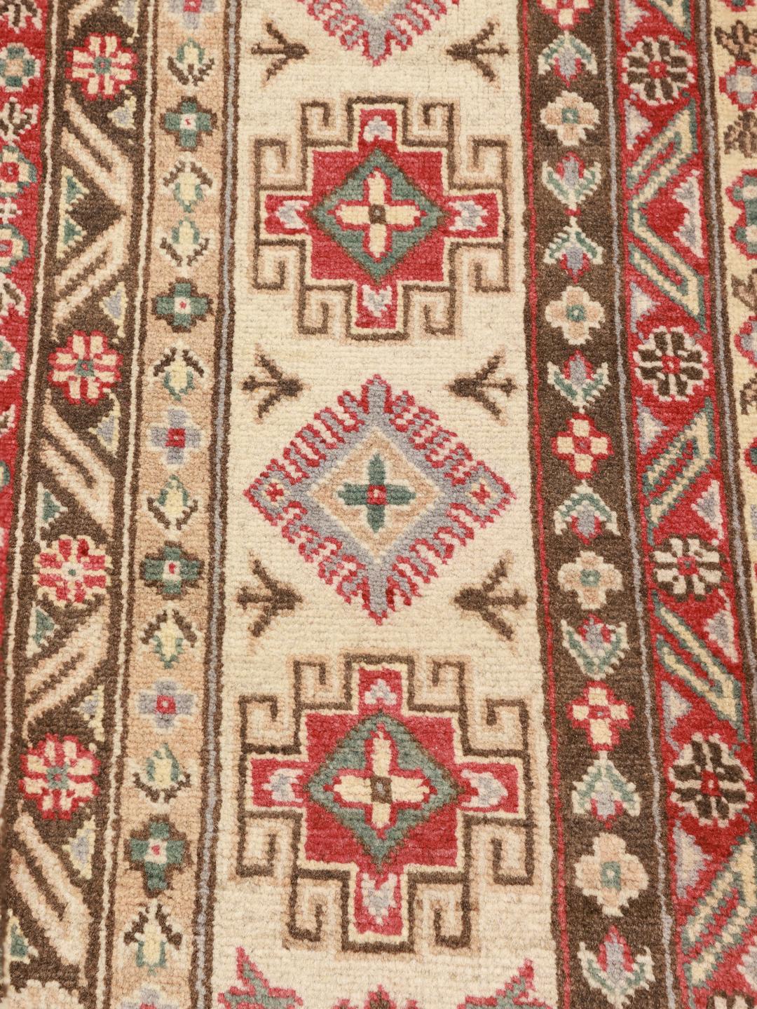 Een groot, handgeknoopt Kazak-tapijt uit Afghanistan in grijstinten en rood.