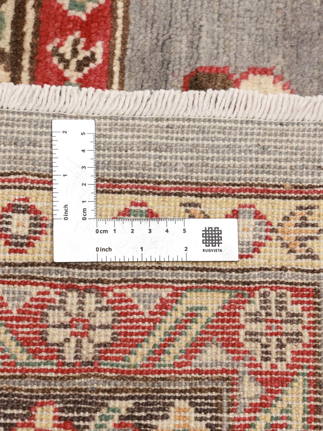Een groot, handgeknoopt Kazak-tapijt uit Afghanistan in grijstinten en rood.