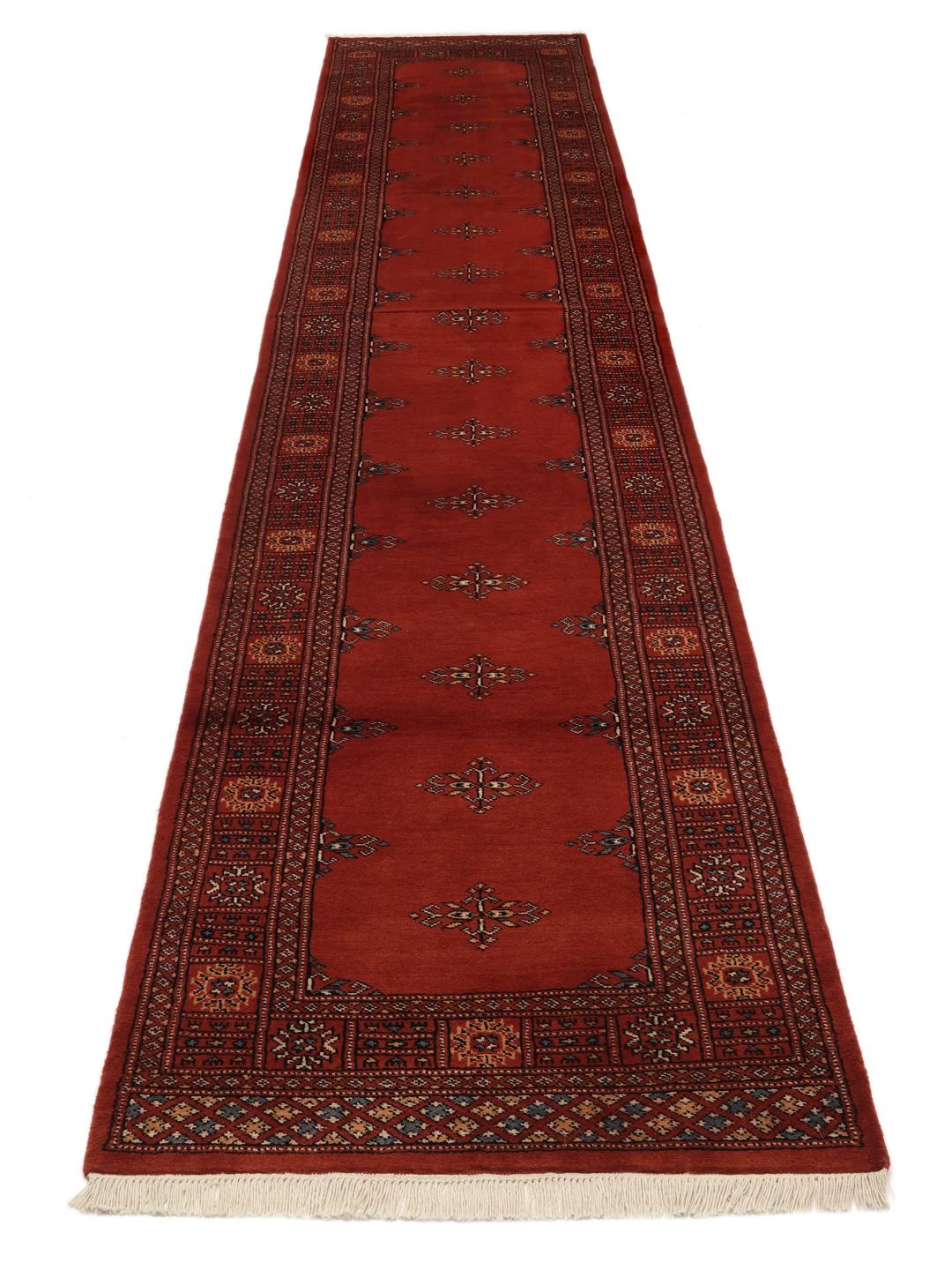 Hand-knotted Pakistan Bokhara runner in deep red with traditional motifs.