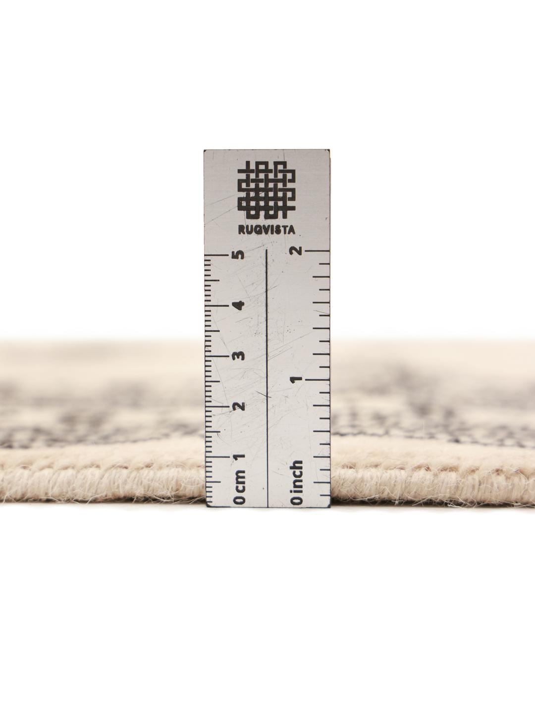 A long, beige hand-knotted runner from Pakistan with black repeating motifs.