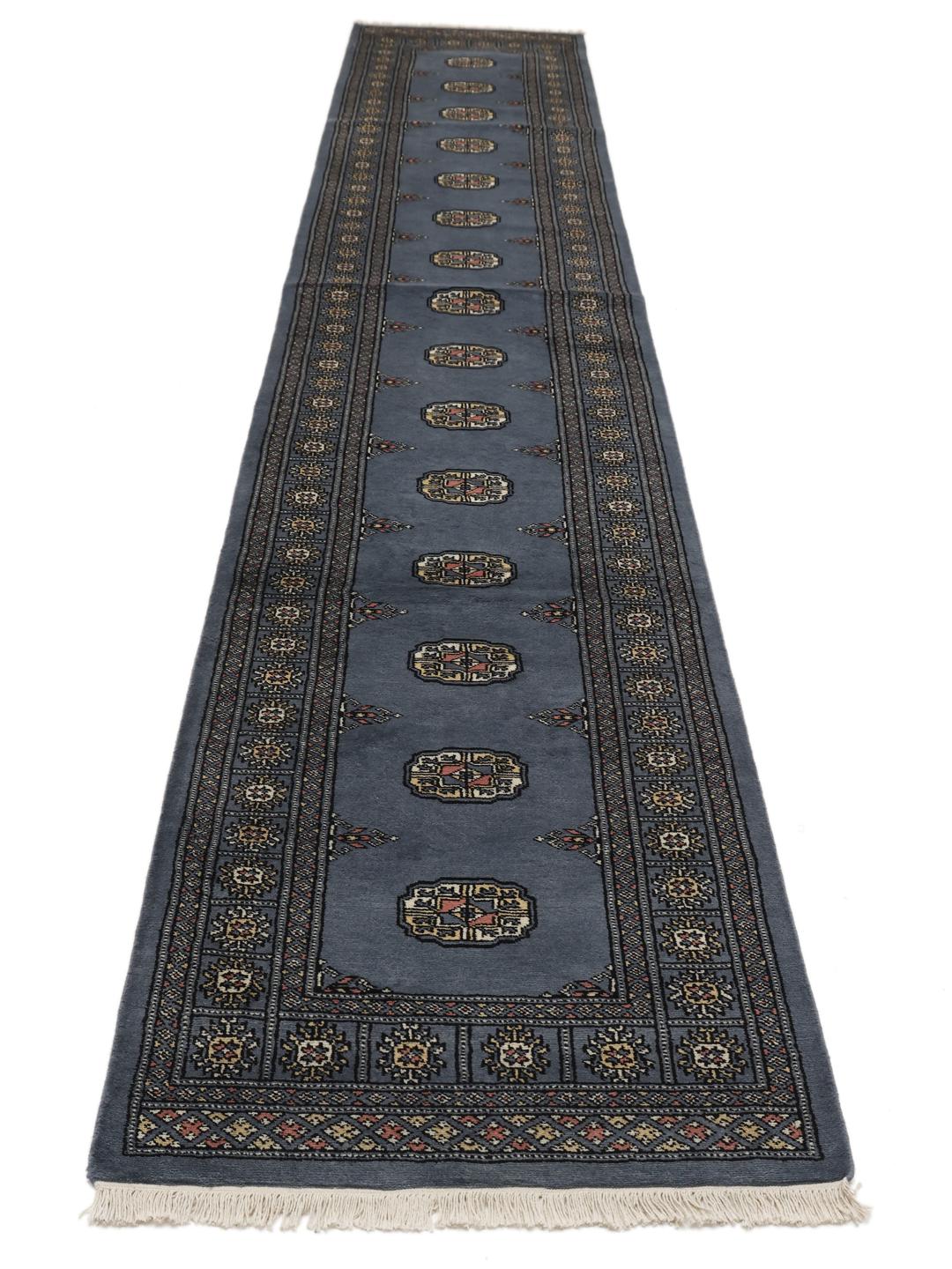 A long, hand-knotted blue runner rug from Pakistan with traditional patterns.