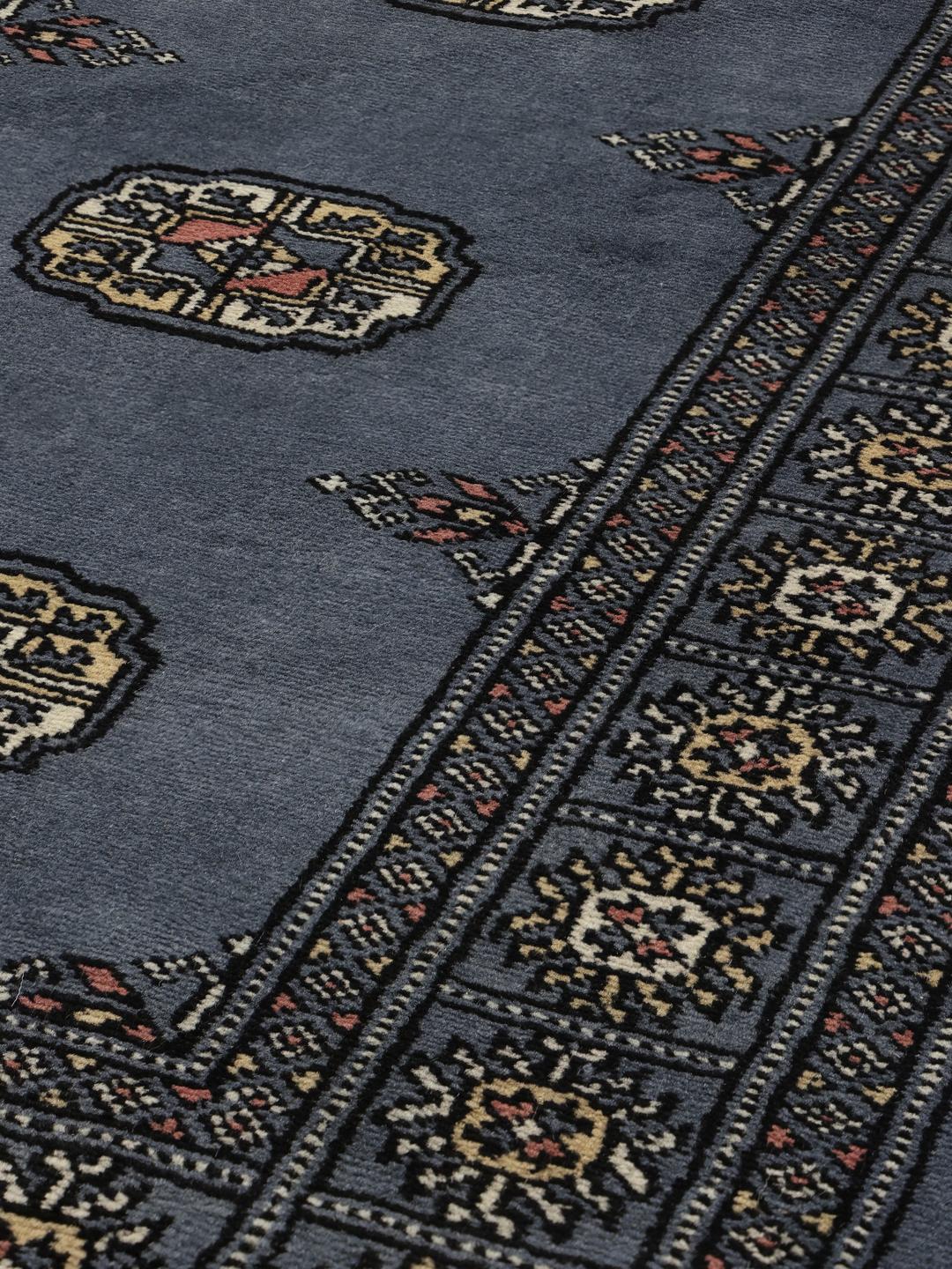 A long, hand-knotted blue runner rug from Pakistan with traditional patterns.