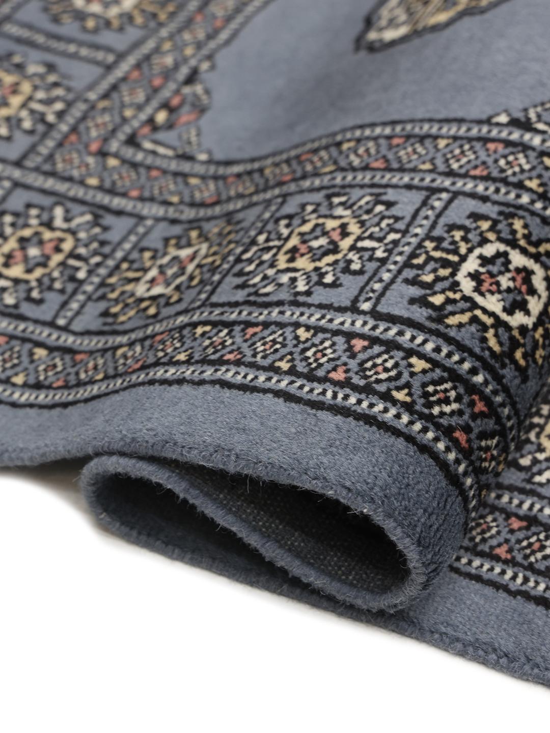 A long, hand-knotted blue runner rug from Pakistan with traditional patterns.