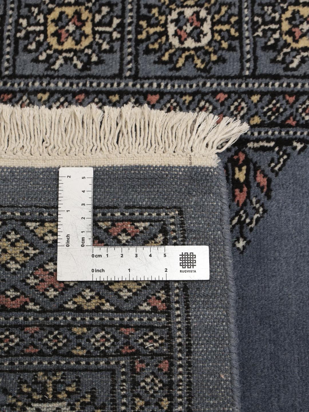 A long, hand-knotted blue runner rug from Pakistan with traditional patterns.
