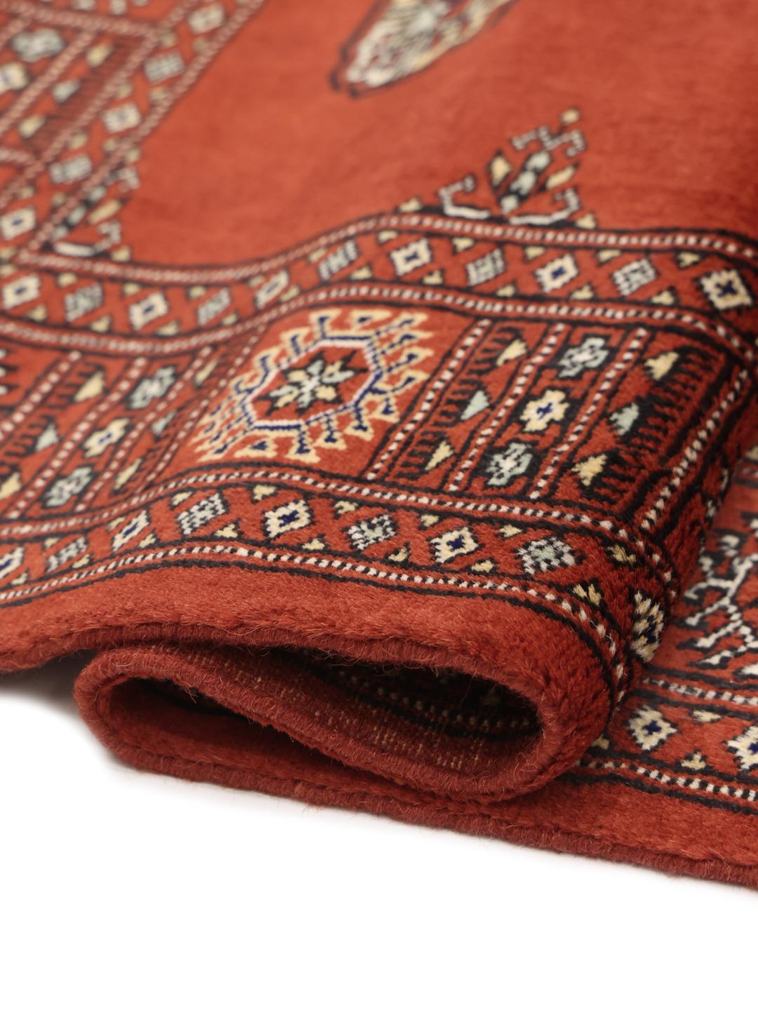 Hand-knotted Pakistan Bokhara rug with a vibrant red field and traditional geometric motifs