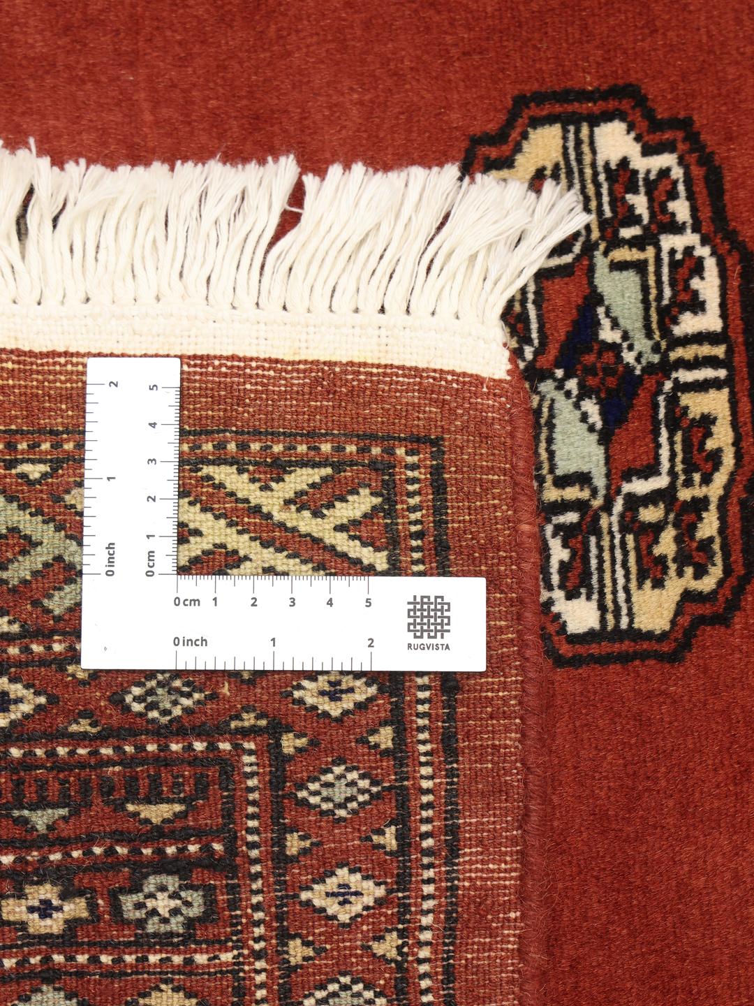 Hand-knotted Pakistan Bokhara rug with a vibrant red field and traditional geometric motifs
