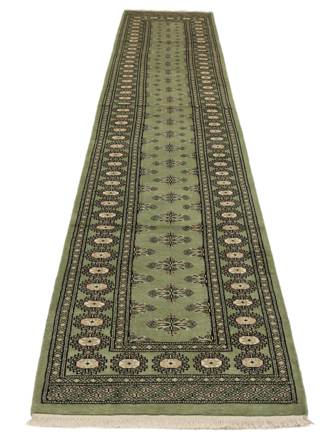 A long, elegant Pakistan Bokhara runner in soft green with traditional motifs.