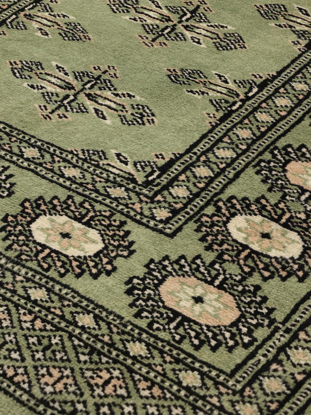 A long, elegant Pakistan Bokhara runner in soft green with traditional motifs.