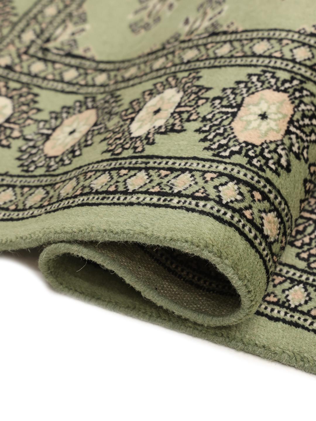 A long, elegant Pakistan Bokhara runner in soft green with traditional motifs.