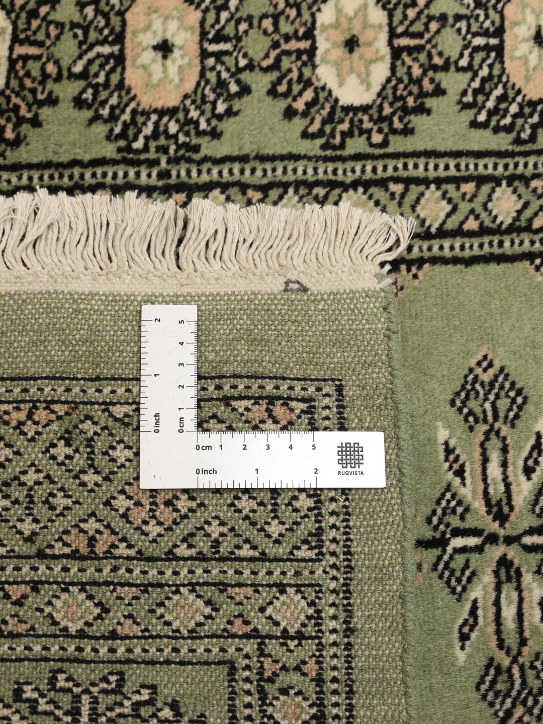 A long, elegant Pakistan Bokhara runner in soft green with traditional motifs.