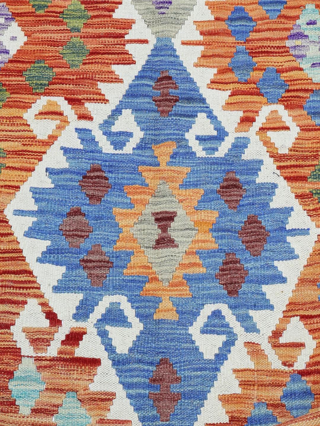 A large, hand-woven Afghan Kelim rug featuring a vibrant geometric pattern in multicolor tones.