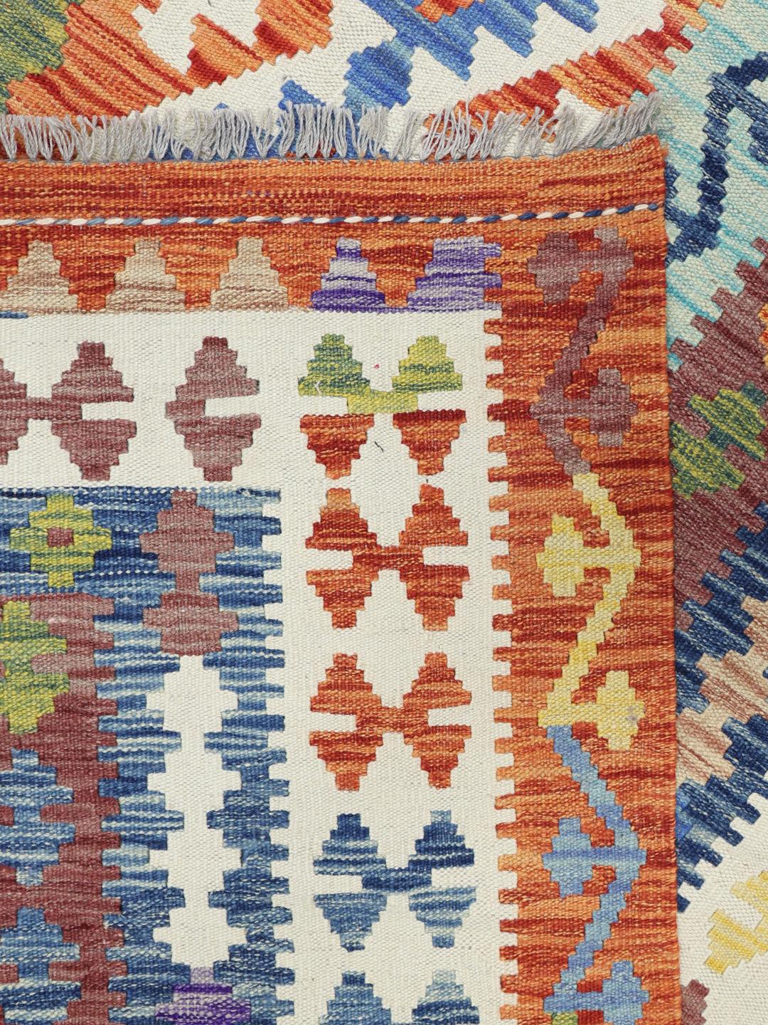 A large, hand-woven Afghan Kelim rug featuring a vibrant geometric pattern in multicolor tones.