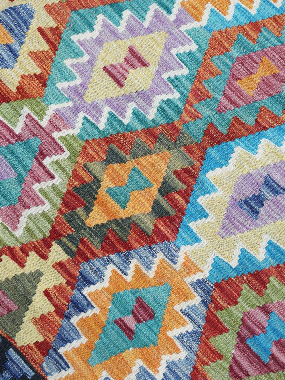 Hand-woven Afghan Kelim rug with vibrant geometric patterns and a multicolor palette