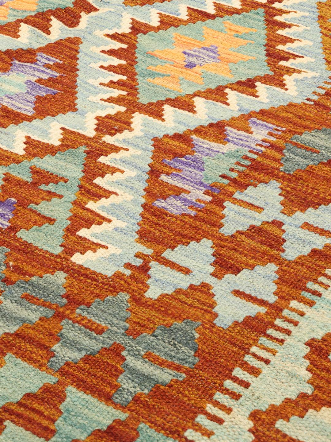 Un tapis Kelim afghan rectangulaire tissé à la main présentant un motif en losange vibrant et multicolore.