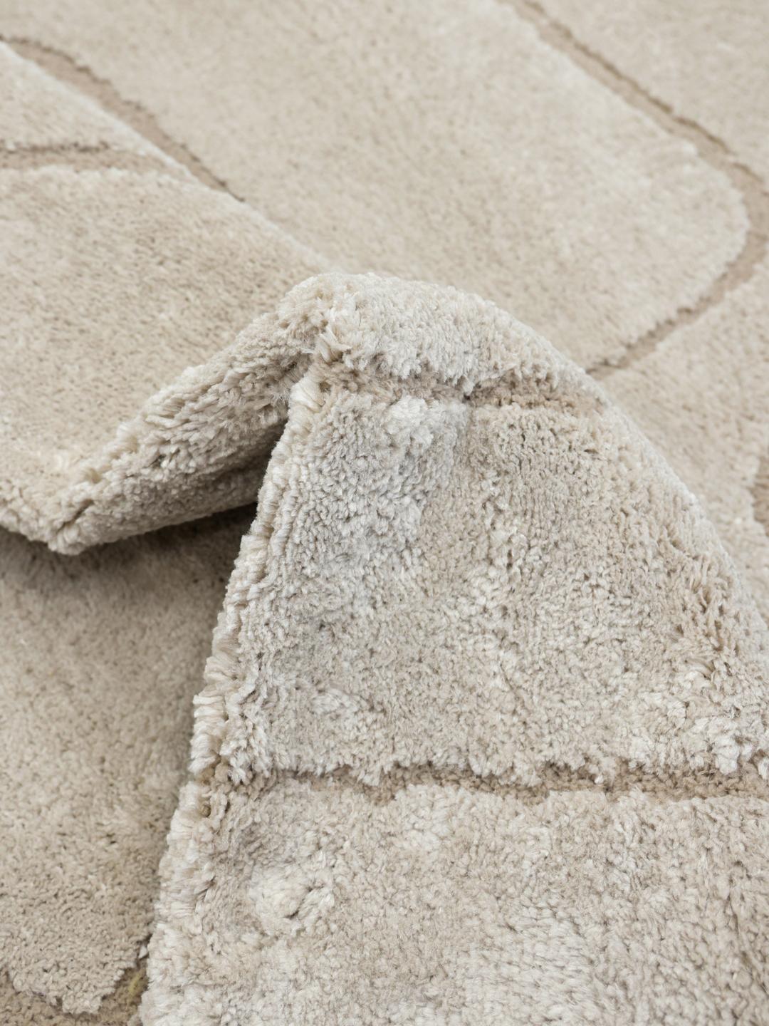 Rond beige tapijt met een textuur van hoge en lage polen