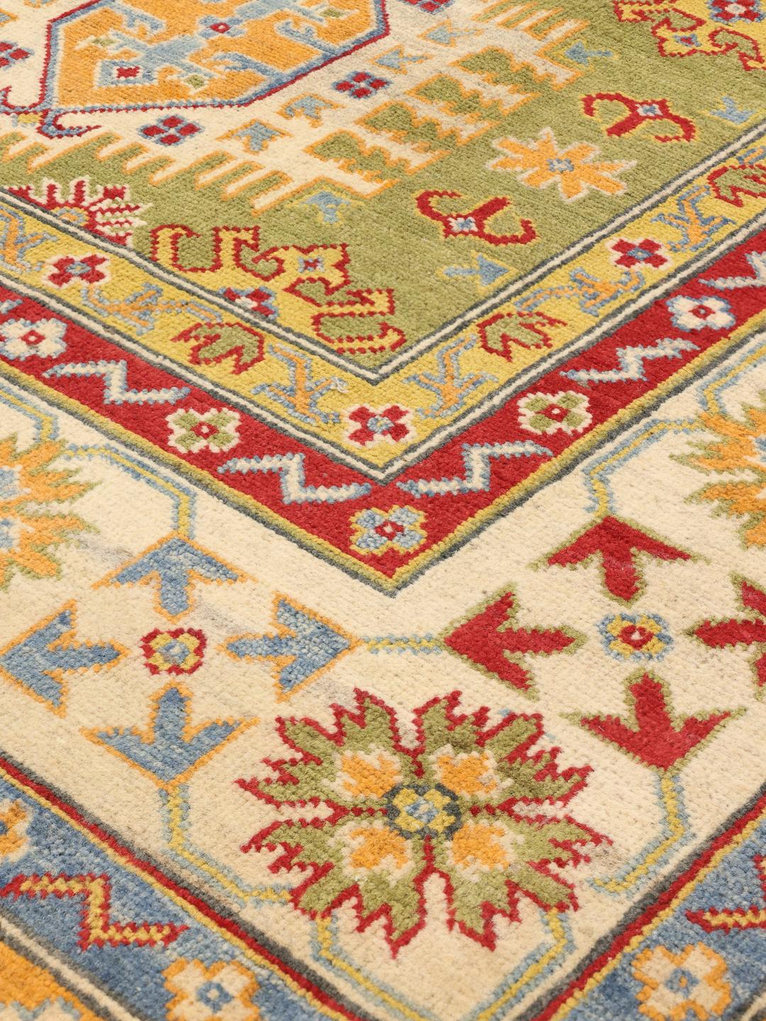 Handgeknoopt Kazak-tapijt uit Afghanistan met een levendig groen veld en geometrische patronen.