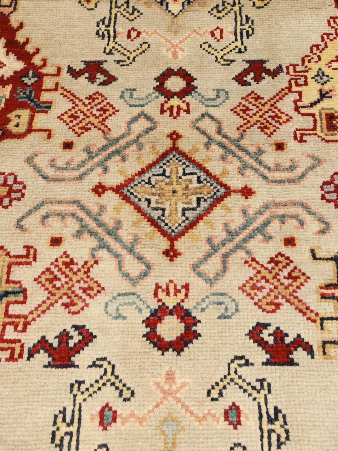 Tapis Kazak noué main originaire d'Afghanistan dans des tons beige et rouge.