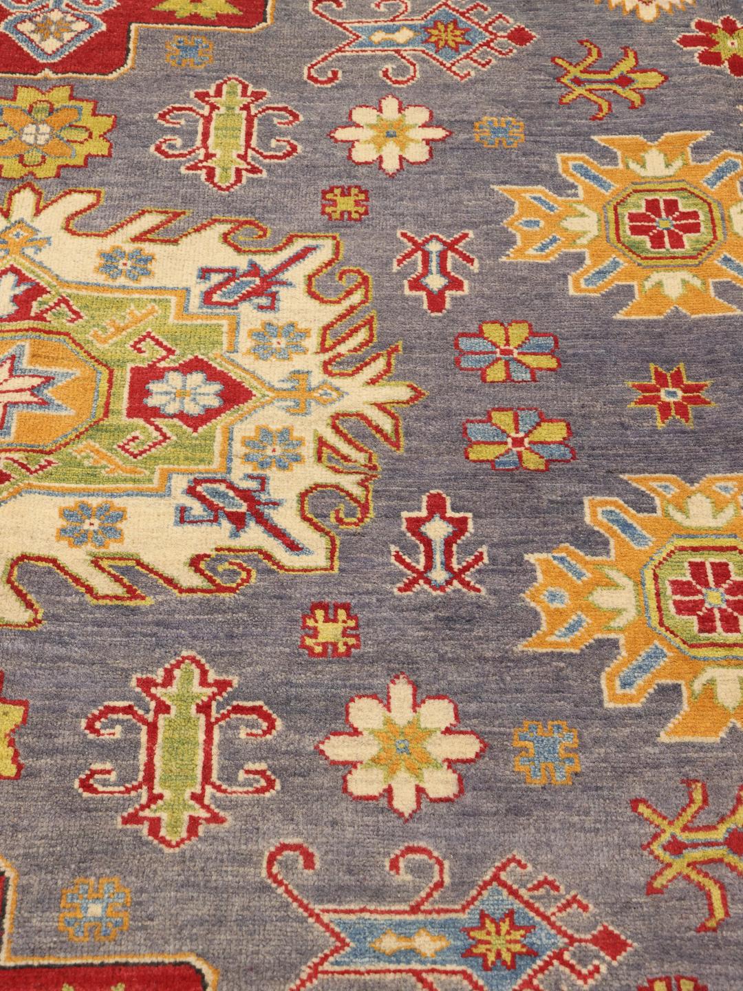 Alfombra afgana Kazak anudada a mano con un campo azul y patrones de medallones geométricos.