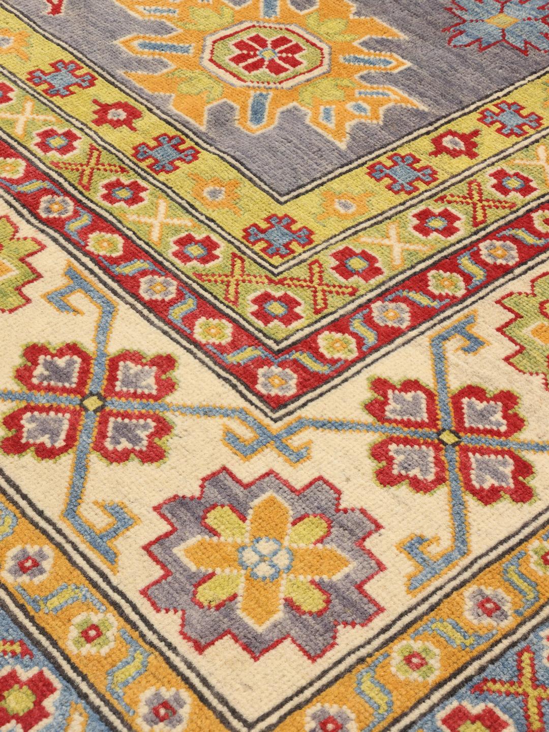 Alfombra afgana Kazak anudada a mano con un campo azul y patrones de medallones geométricos.