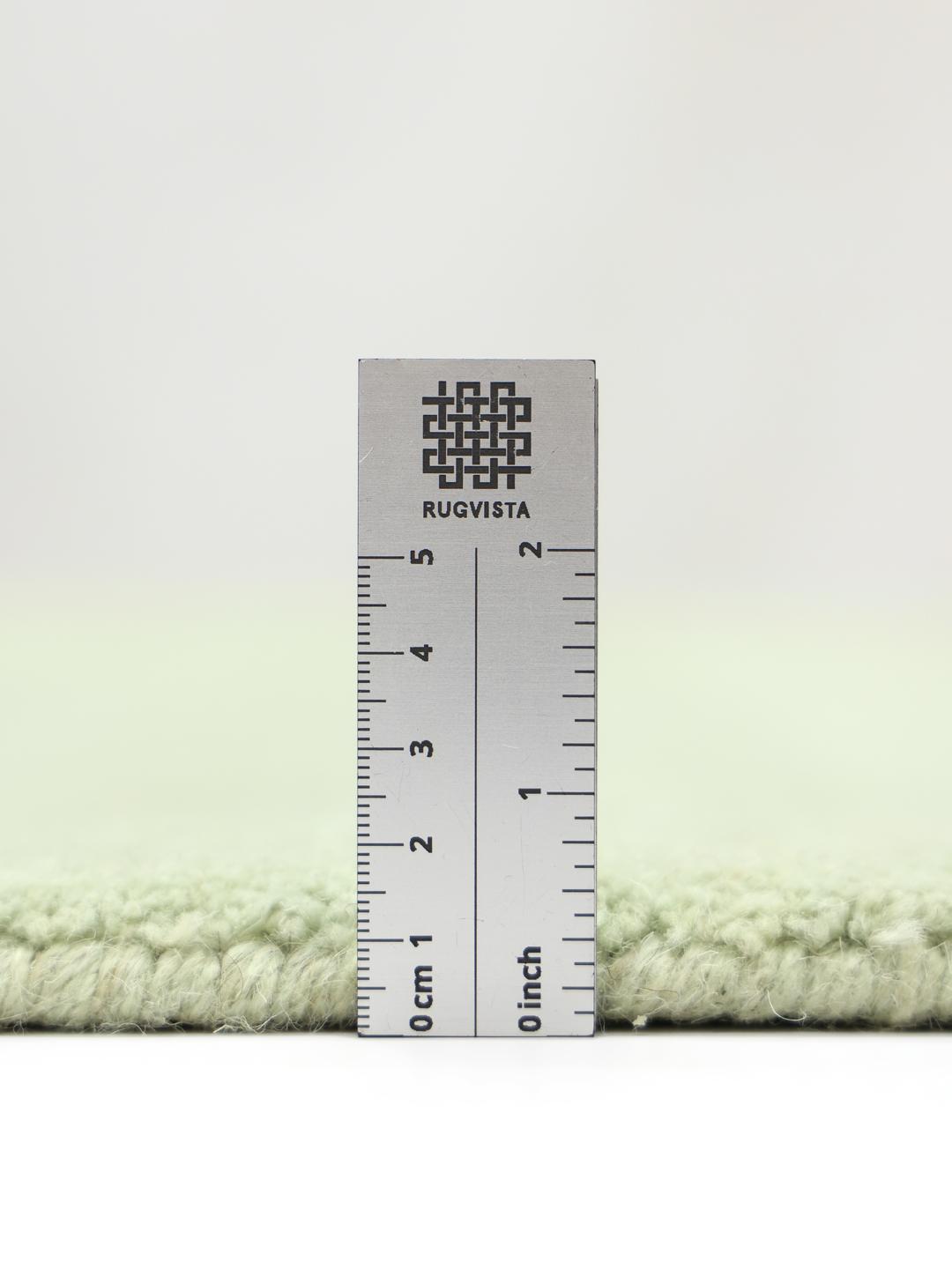 Een handgeweven tapijt in een zachte mintgroene kleur met decoratieve franjes.