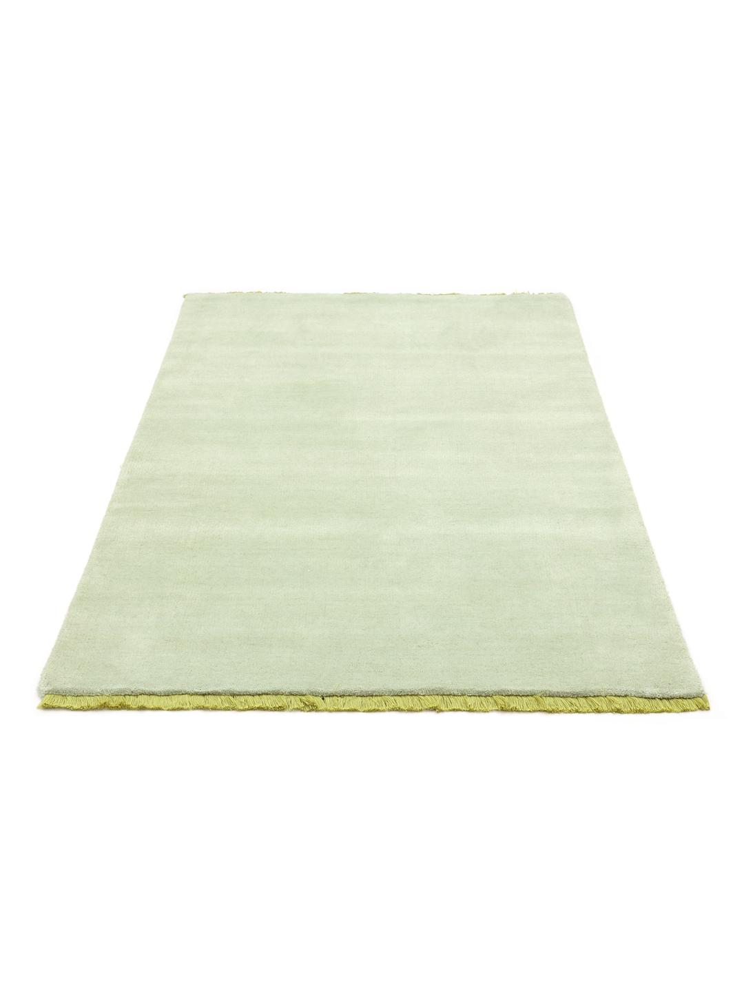 Een handgeweven tapijt in een zachte mintgroene kleur met decoratieve franjes.