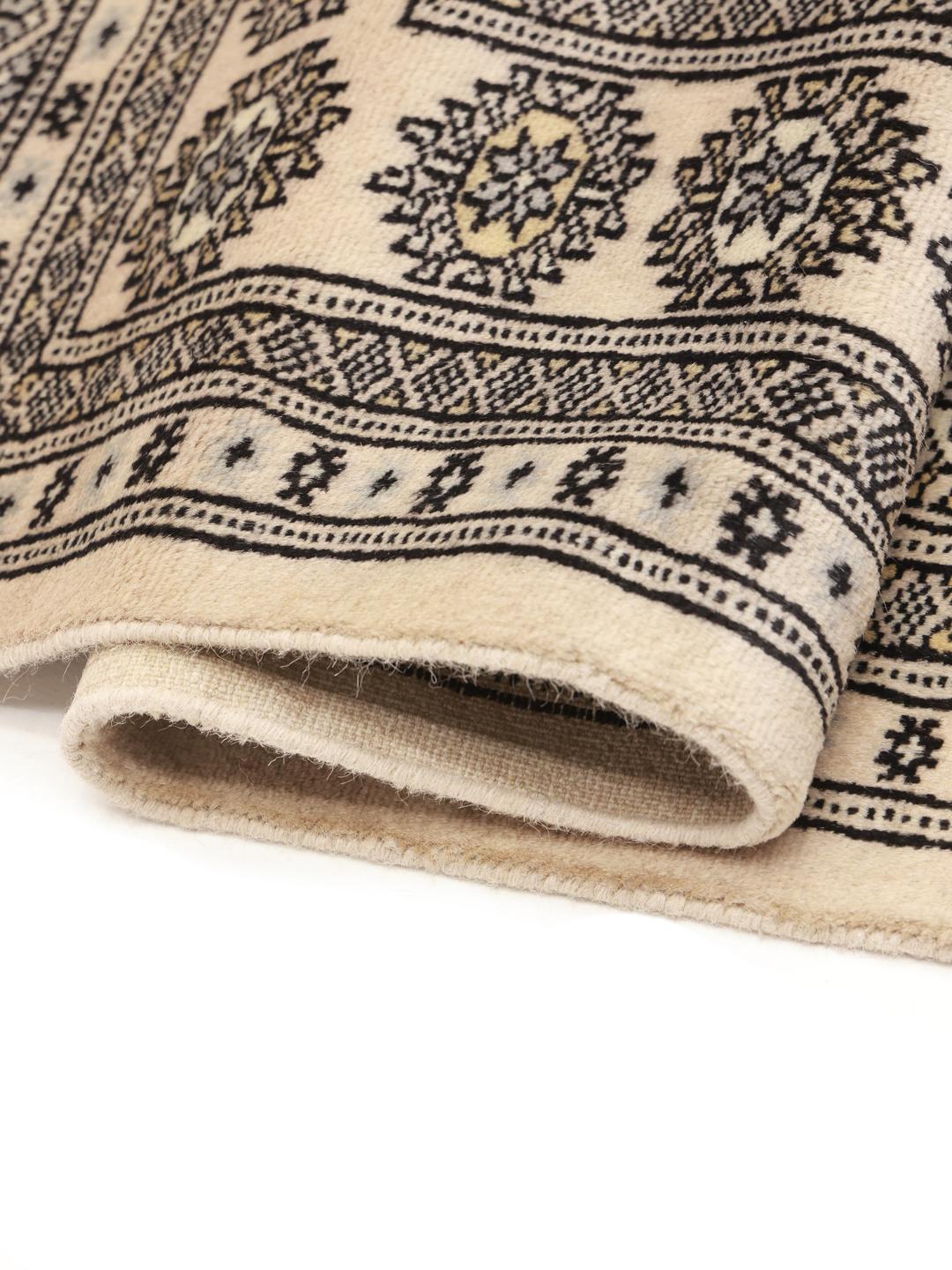 Een vierkant, handgeknoopt Pakistan Bokhara tapijt in beige wol met donkere geometrische motieven.
