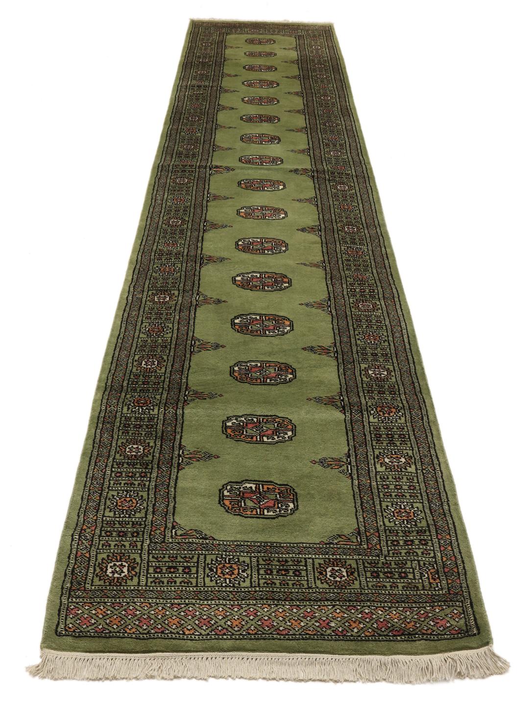 Hand-knotted Pakistan Bokhara runner in green with traditional geometric motifs.